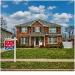 Investissement locatif aux USA : Une image d'une maison à vendre aux États-Unis. La maison est une maison en briques de deux étages avec une clôture en bois blanc et une pelouse verte. Le ciel est bleu et il y a des nuages dans le ciel. L'image est en couleur et est prise d'un point de vue grand angle.